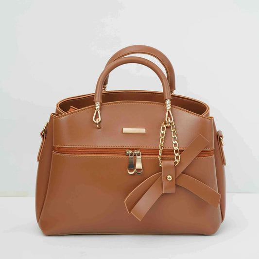 Brown leather handbag with gold chain, bow accent, and dual handles on white background