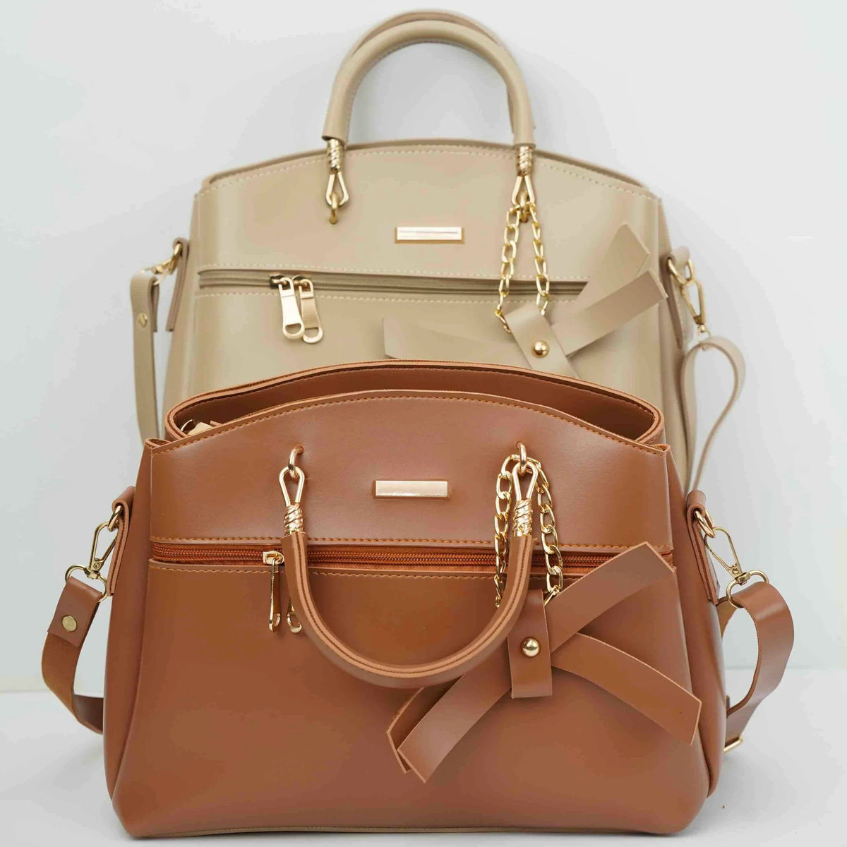 Two stylish handbags in tan and beige with gold chain accents and bow details