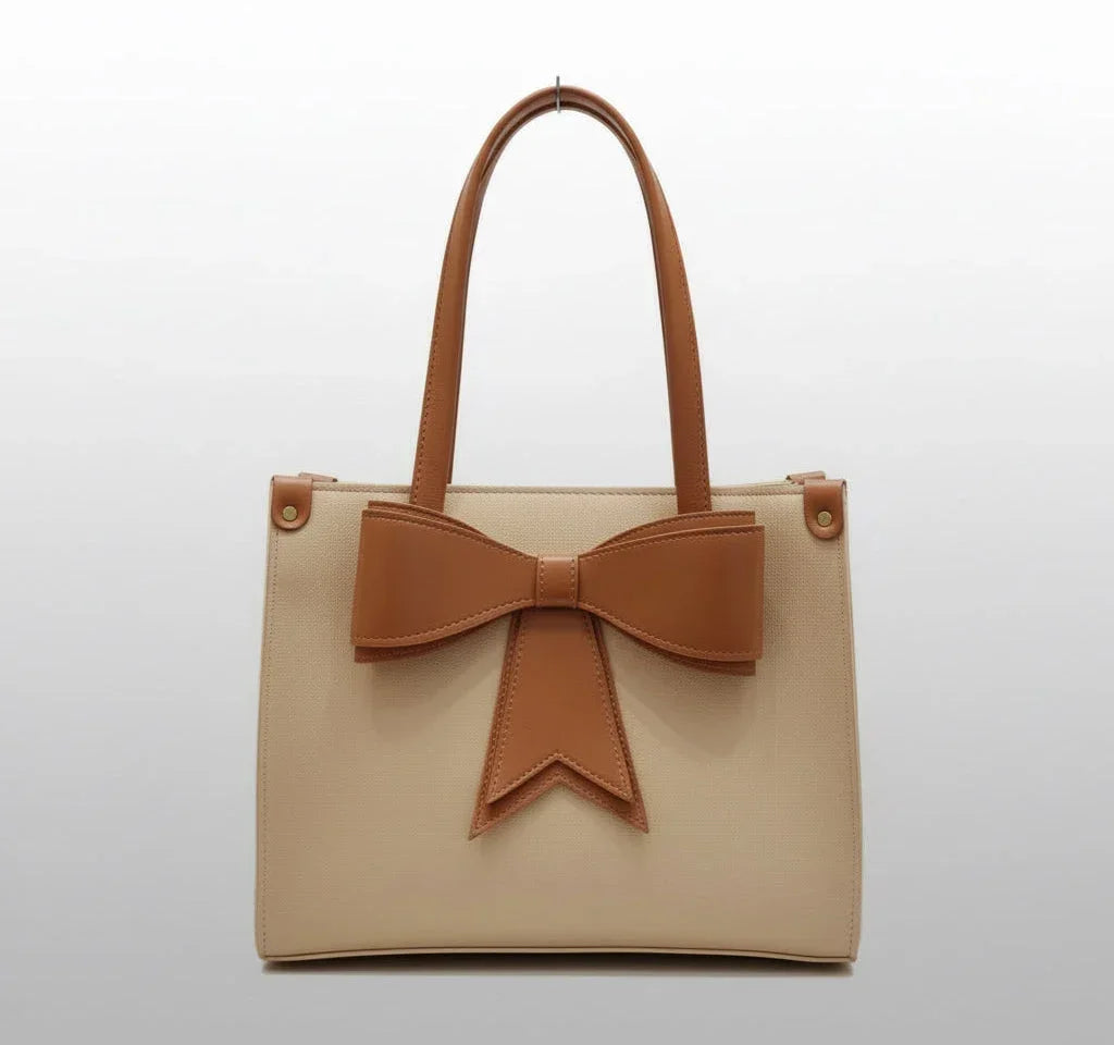 Beige tote bag with brown handles and a large brown bow on the front, minimalist style