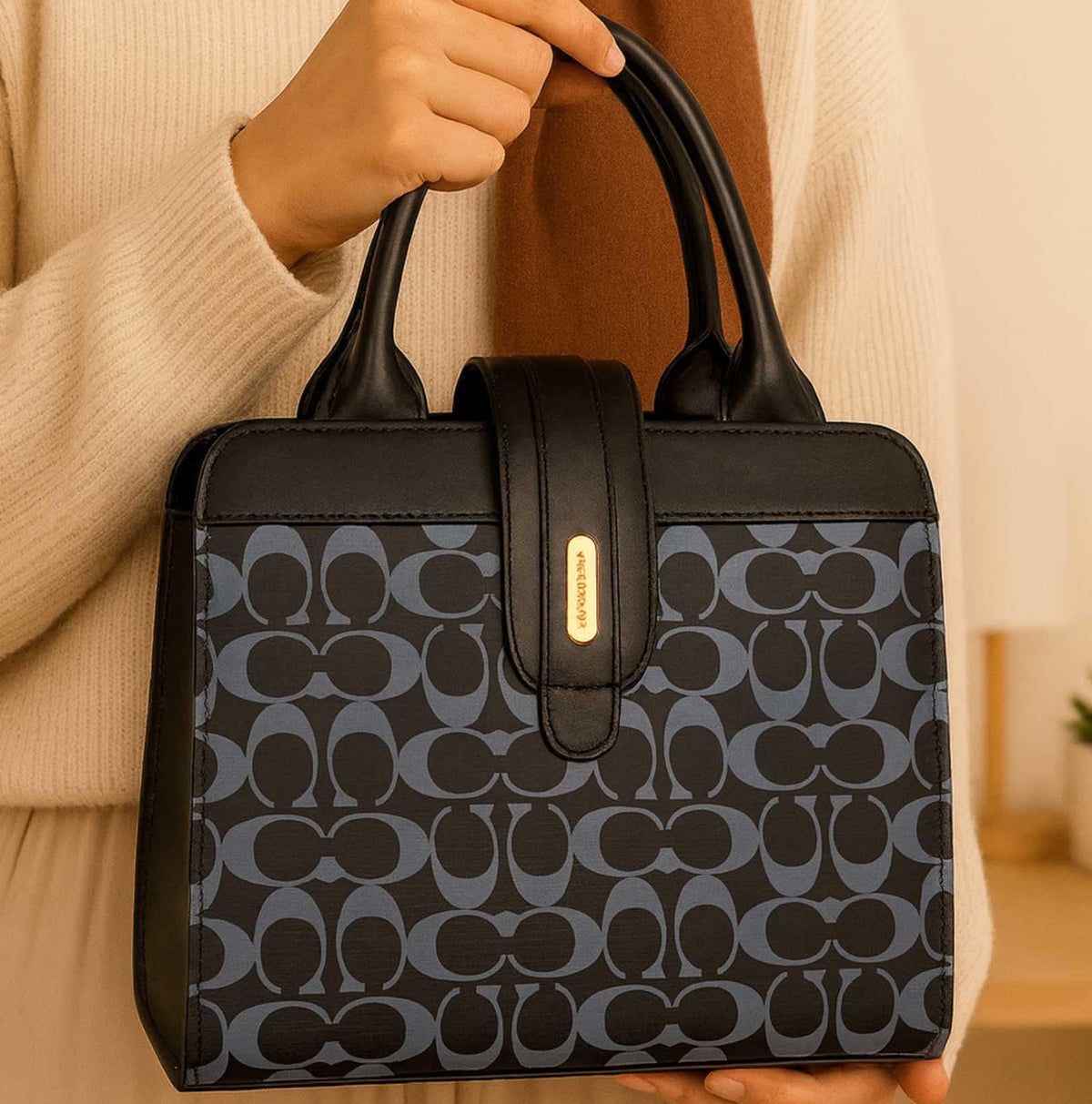 Woman holding a black and blue patterned handbag with gold accents in a cozy indoor setting