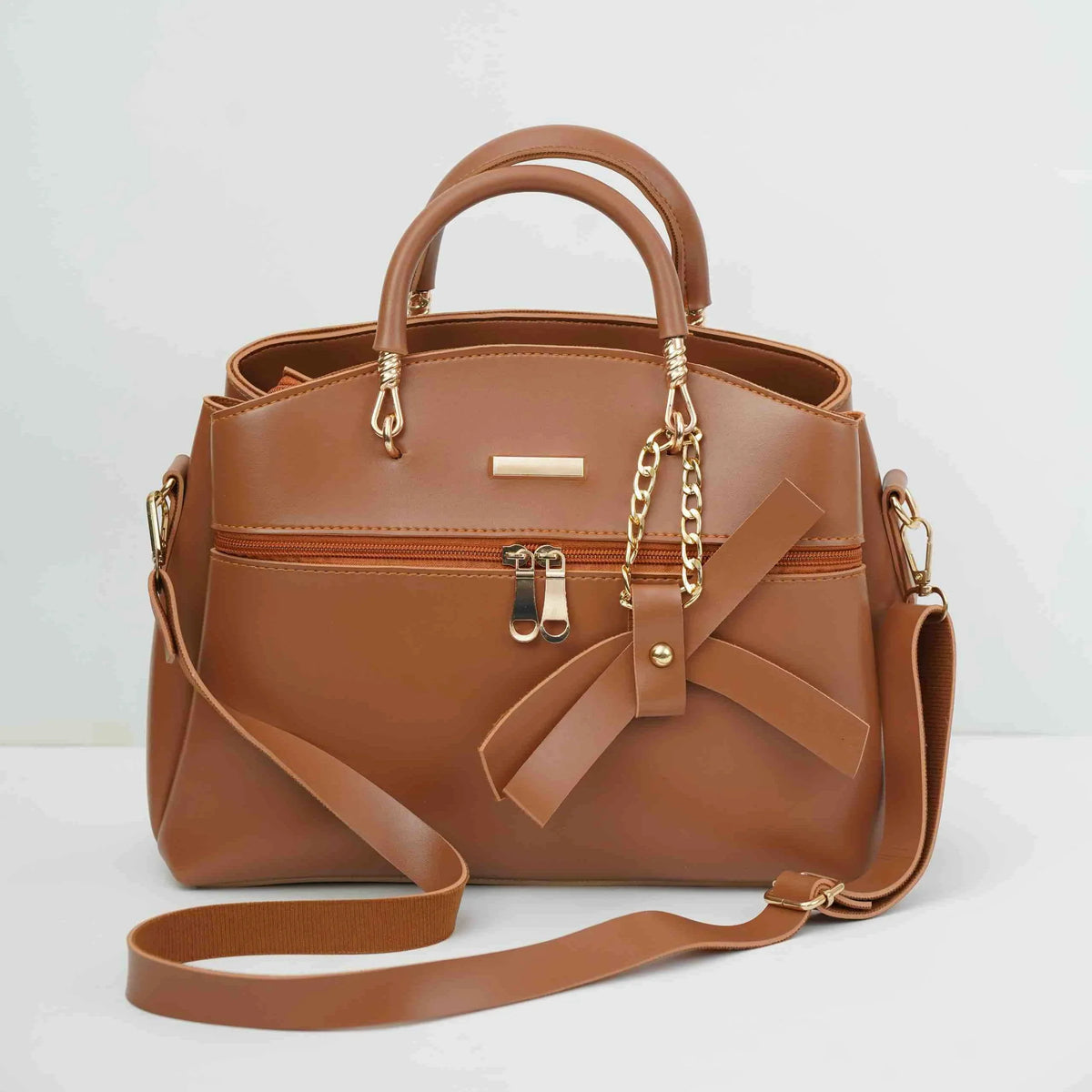 Brown leather handbag with gold chain accents, front zipper, and decorative bow detail